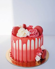 a red cake with white frosting and strawberries on top, sitting on a gold plate