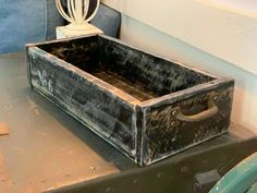 an old wooden box sitting on top of a metal table next to a blue chair