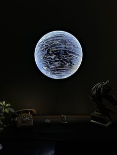 a desk with a phone and a clock in the dark, lit up by a light bulb