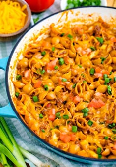 a casserole dish with pasta and vegetables in it on a blue towel next to green onions