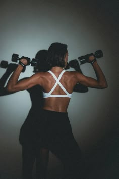 a woman holding two dumbs in front of her back