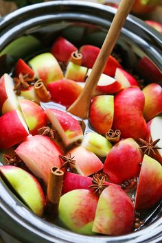 apples and cinnamon sticks are in a pot full of water with an apple slice sticking out of the top