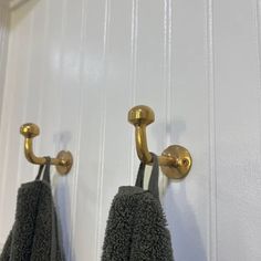 two towels are hanging on the wall with hooks in front of them and one has a gold handle