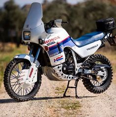 a white and blue motorcycle parked on top of a dirt road