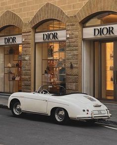 an old white car parked in front of a dior store