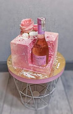 a cake with pink frosting and flowers on it sitting on top of a table