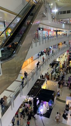 an overhead view of people walking around in a shopping mall with escalators and stairs