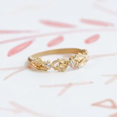 a yellow gold ring with three diamonds on it's sides and leaves in the middle