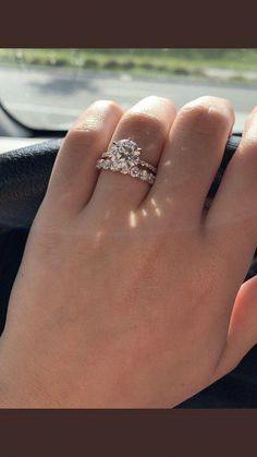 a woman's hand on the steering wheel of a car with a diamond ring