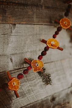 oranges and cinnamon sticks are arranged on a wooden wall with christmas decorations around them