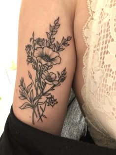 a woman's arm with flowers and leaves tattooed on the back of her shoulder