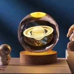 a glass globe with an image of the solar system in it and two small figurines next to it