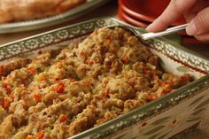 a casserole dish with meat and vegetables in it sitting on a table next to plates