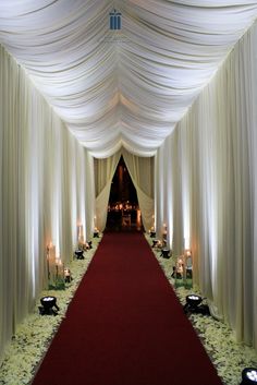 a red carpeted aisle with white drapes and candles