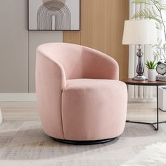 a pink chair sitting on top of a white rug next to a table and lamp