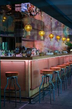 a bar with several stools in front of it and lights hanging from the ceiling