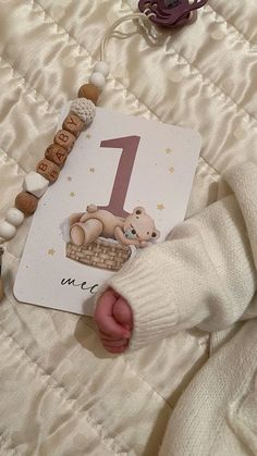 a baby's first birthday card laying on top of a bed with teddy bears