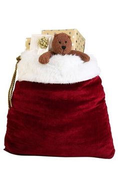 a teddy bear sitting on top of a red bag with white fur and gold trim