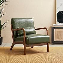 a green leather chair sitting in front of a painting on the wall next to a potted plant