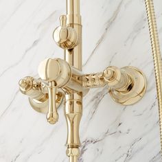 a gold faucet and shower head on a white marble counter top with brass fixtures