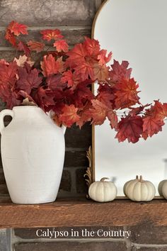 Stone fireplace with gold mirror, white mini pumpkins and red maple leaves in a white vase. Sherwin Williams Naval, Layer Artwork, Elegant Fall Decor, Fall Feeling, Mantel Decorating, Mantel Ideas, Fireplace Mantel Decor