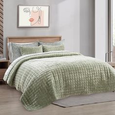 a bed with a green comforter and pillows