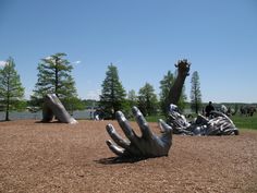 a large metal hand laying on top of a dirt field