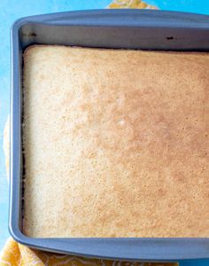 a blue pan filled with cake sitting on top of a table next to an orange napkin