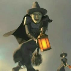 two people dressed as witches flying through the air with a lantern in their hands and one holding a broom