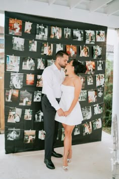 a man and woman standing next to each other in front of a wall with pictures on it