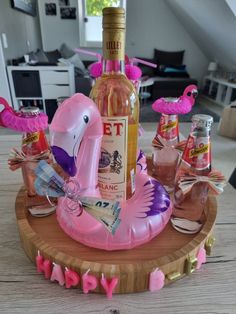 a pink flamingo inflatable wine bottle holder on a wooden table with personalized items