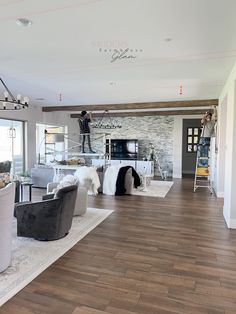 a living room with hard wood floors and white furniture in front of a large window