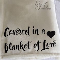 embroidered in a blanket of love on top of a white table cloth with black lettering