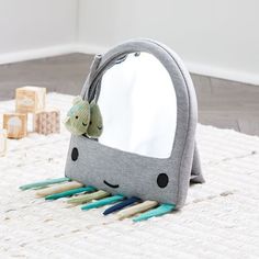 a gray whale shaped mirror sitting on top of a white rug next to wooden blocks