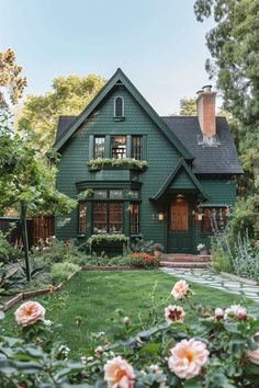 a green house with lots of flowers in the front yard