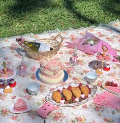 a table topped with cakes and desserts on top of a floral covered table cloth