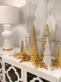 gold and white christmas trees are on top of a dresser