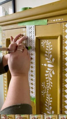 someone is painting the side of a yellow cabinet