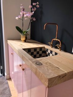 a kitchen with pink cabinets and a checkerboard countertop in the center, next to a sink