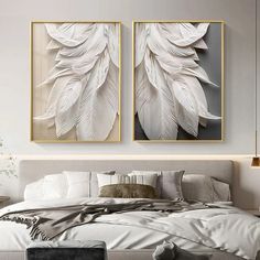 two paintings on the wall above a bed in a room with white sheets and pillows