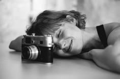 a woman laying on the floor with her head down next to a camera and taking a photo