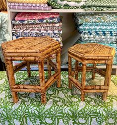 two small stools sitting on top of a green and white rug next to pillows