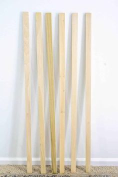 three wooden sticks sticking out of the ground next to each other in front of a white wall