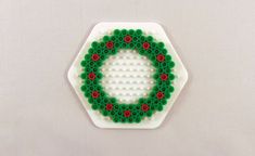 a green and red beaded ornament sitting on top of a white surface