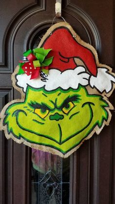 the grinch door hanger is decorated with santa's hat