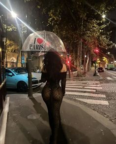 a woman is walking down the street at night with an umbrella in her hand,