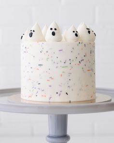 a white cake with sprinkles and three ghost faces on it's side