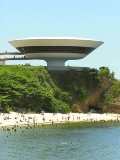 people are on the beach and in the water near a large structure that looks like a spaceship