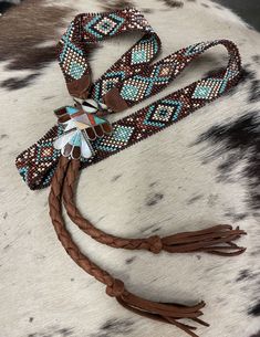 VERY RARE VINTAGE ZUNI BOLO SLIDE ON THIS ONE OF A KIND ORIGINAL HANDMADE HAT BAND MADE BY MYSELF, LynneLondon, www.WILDWESTART.BIZ THE SLIDE IS OF TURQUOISE, RED CORAL, MOTHER OF PEARL, ONYX, and ABALONE INLAY. IN EXCELLENT CONDITION (vintage) THE MEDIUM BROWN DEERSKIN LEATHER IS FINELY BRAIDED TO COME TOGETHER IN THE BACK OF YOUR HAT IN A BOLO STYLE HATBAND. FULLY ADJUSTABLE TO FIT ANY SIZE HAT THIS BAND IS MADE OF BEAUTIFUL GLASS #11 BEADS, 7/8" wide MY ORIGINAL DESIGN TEAL, TURQUOISE, DARK B Native American Hat Bands, Beaded Hat Band Patterns, Burned Hats, Cowboy Hat Bands, Beadwork Ideas, Beaded Hat Bands, Beading Loom, Band Ideas, Hat Bands