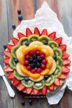 a fruit tart topped with sliced kiwis, strawberries and blueberries